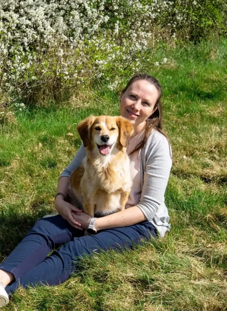 Tierphysiotherapeutin Cindy Mayer mit Hund im Gras sitzend